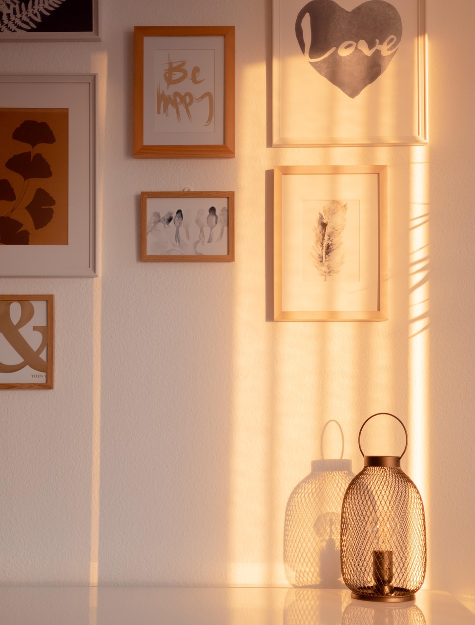 Parede com quadros emoldurados iluminada pelo sol da tarde.