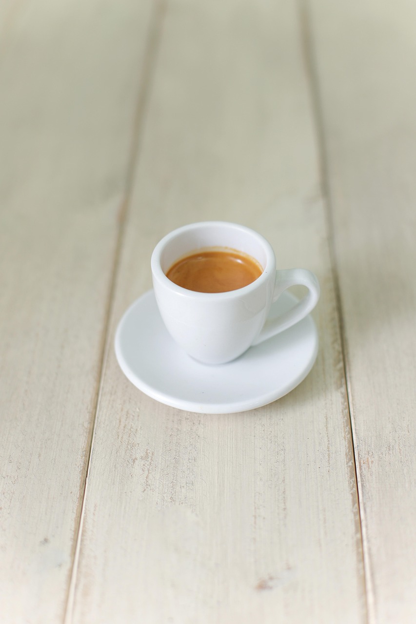 Xícara de café expresso sobre mesa de madeira clara.