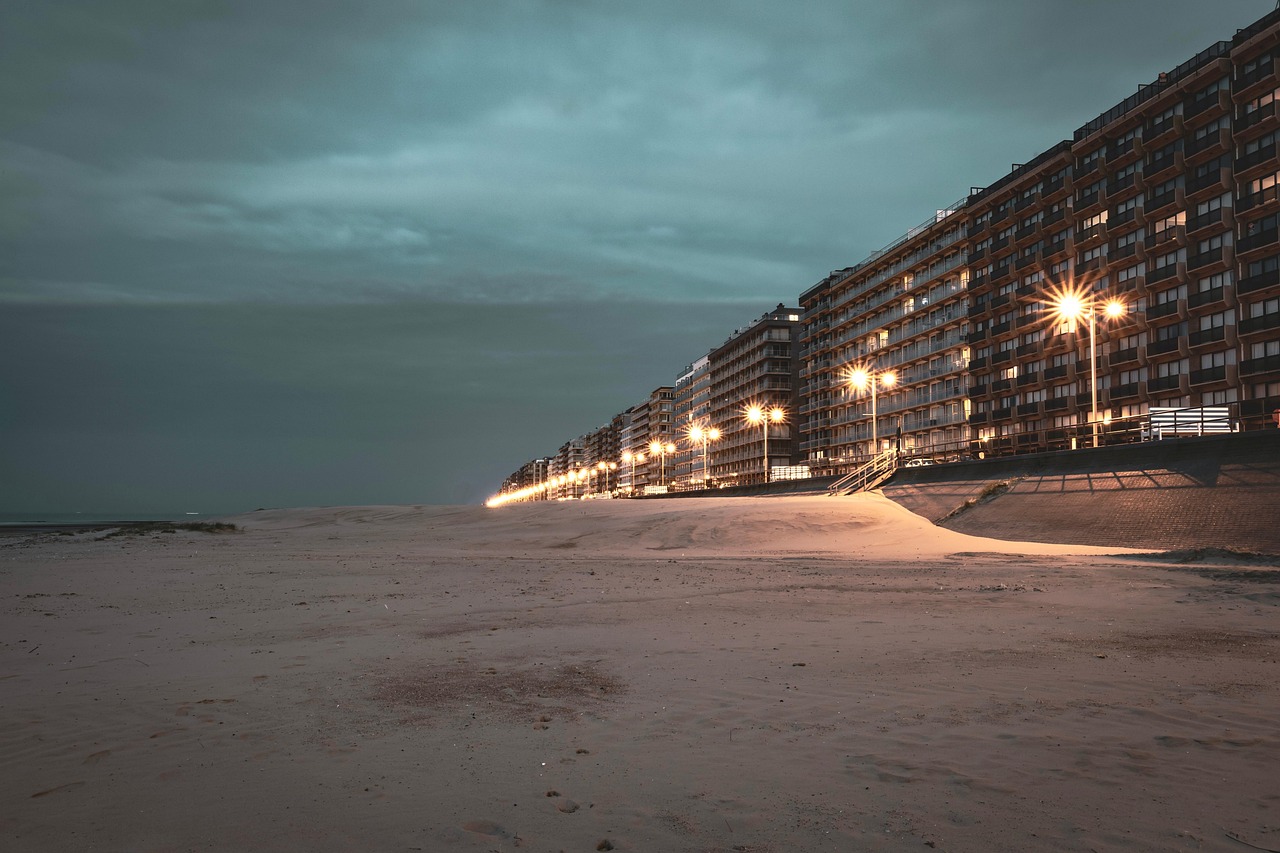 Praia ao entardecer com prédios iluminados ao longo da orla.