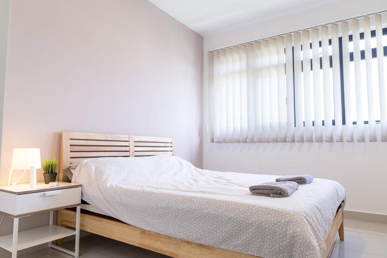 Quarto claro com cama de madeira e janela ampla.